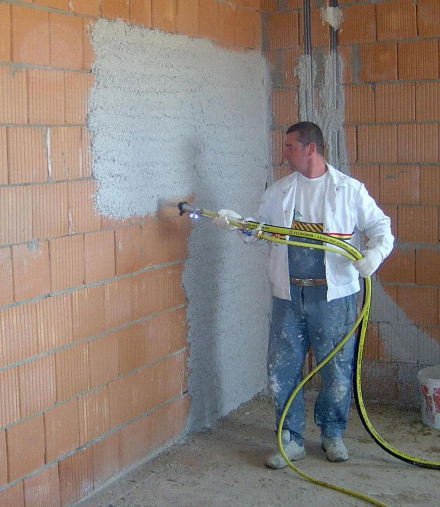 Technician applying spray foam insulation to an interior wall for improved energy efficiency.