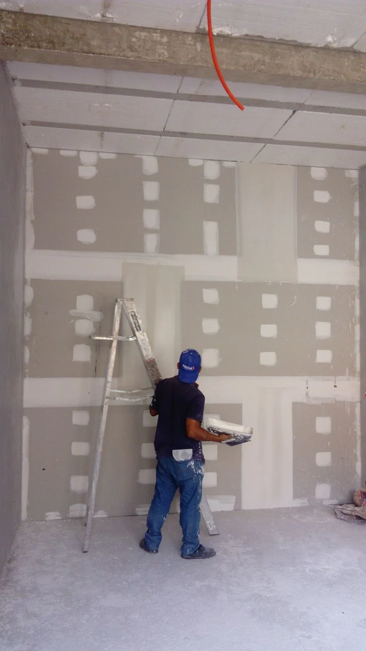 Drywall contractor applying joint compound to interior walls during commercial drywall finishing and construction project.