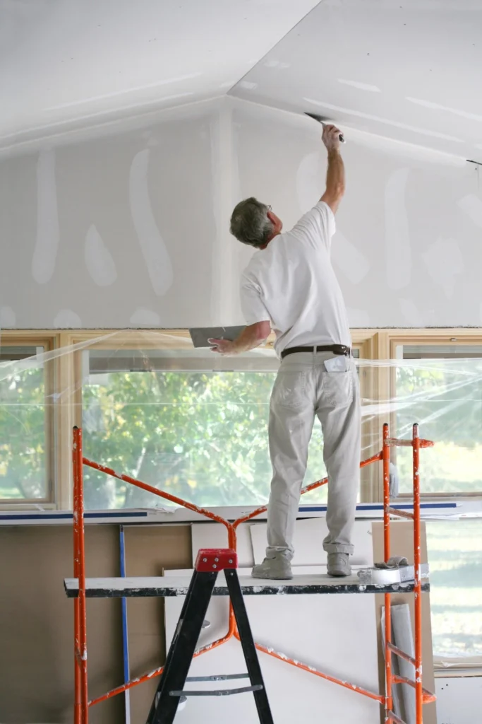 Drywall contractor finishing ceiling joints and seams during a residential interior renovation.