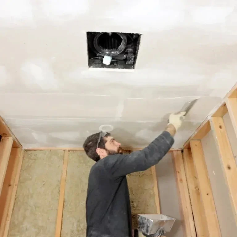 Drywall contractor applying joint compound to a ceiling during residential drywall finishing and basement remodeling project.