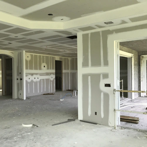 Interior drywall installation in a residential home showing finished walls, ceilings, and taped drywall joints during construction.